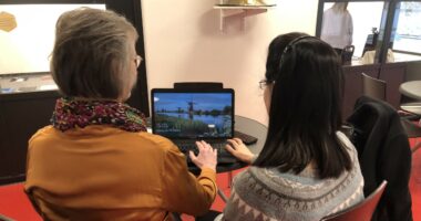 En äldre kvinna och en yngre sitter tillsammans framför en laptop