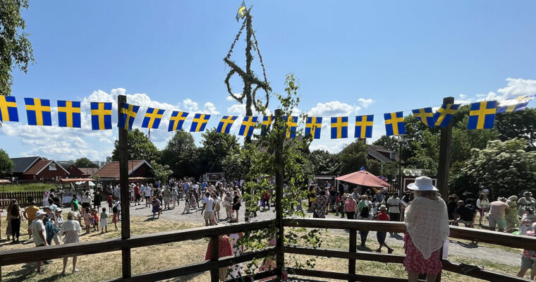 dansbanan på Akalla by, svenska flaggvimplar och midsommarstången i bakgrunden