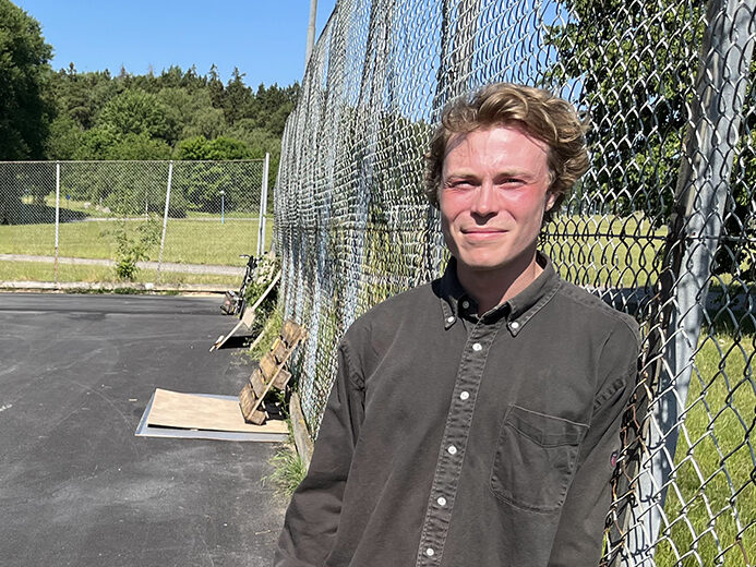ung man står på asfalterad plan som ska bli skateboardpark