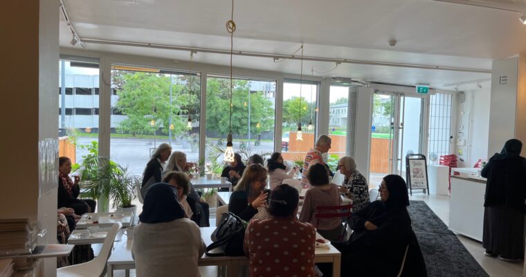 Många kvinnor fikar i konsthallen i motljus.