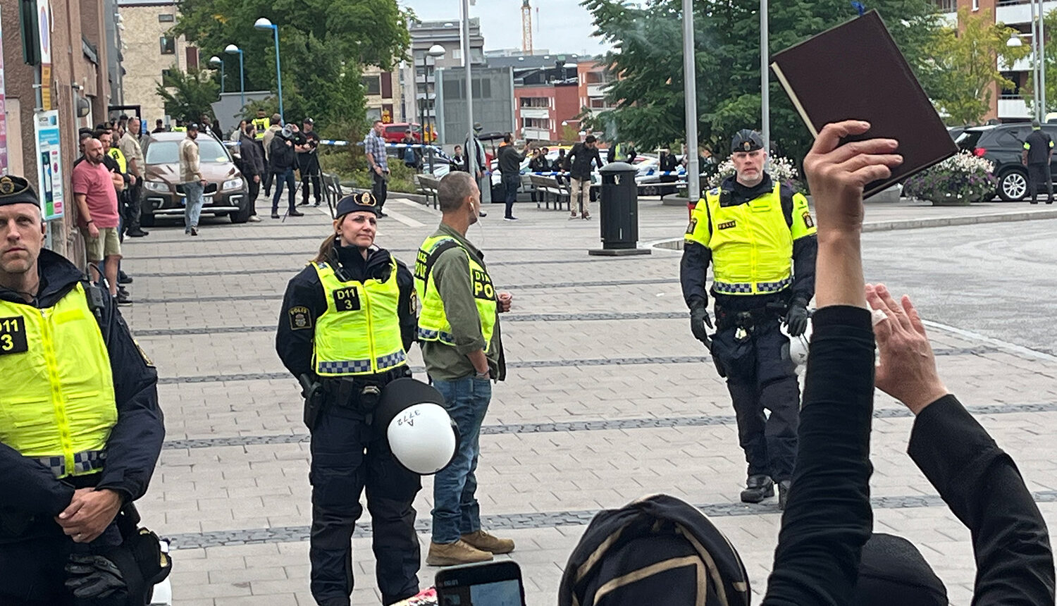 människor protesterar mot koranbränning framför poliser