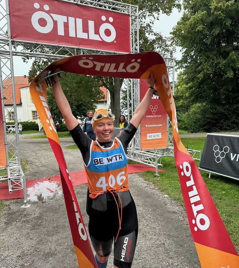 Ung kvinna håller armarna i luften efter att ha vunnit ett lopp.