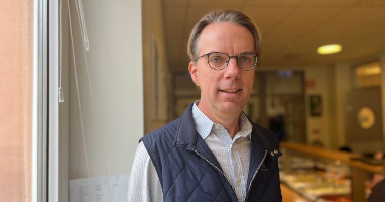 En medelåldersman som står i en skolmatsal.
