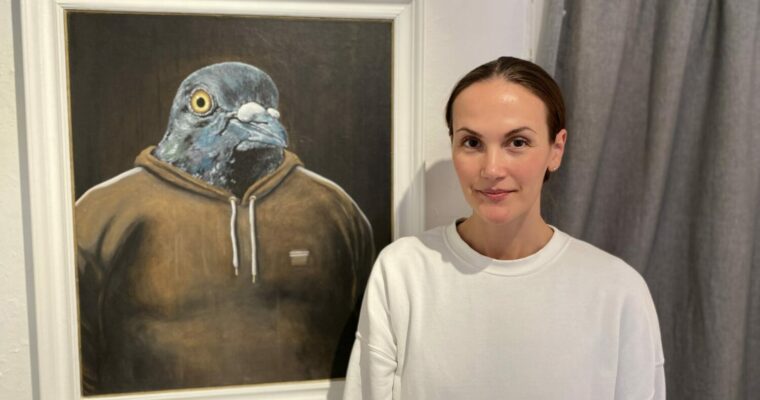Kvinna som står bredvid en tavla med fågelmotiv