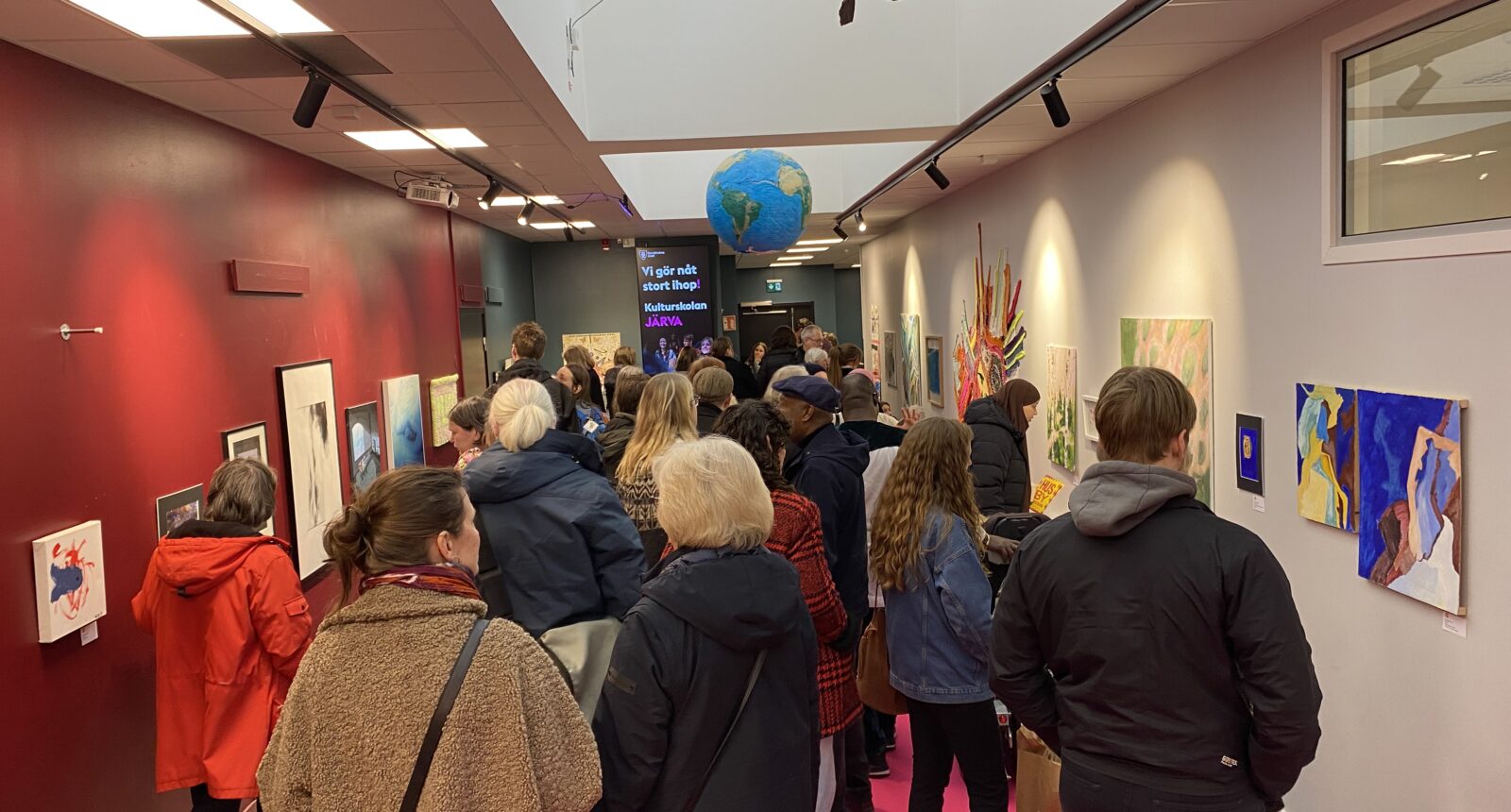 Människor som står i en foaje och tittar på konst på väggarna