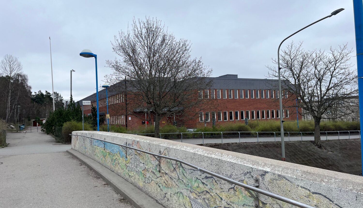 En röd tegelbyggnad, en skola, syns på avstånd.