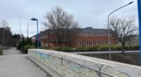 En röd tegelbyggnad, en skola, syns på avstånd.