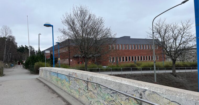 En röd tegelbyggnad, en skola, syns på avstånd.