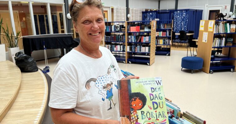 kvinnlig skolbibliotekarie står och håller i en bok