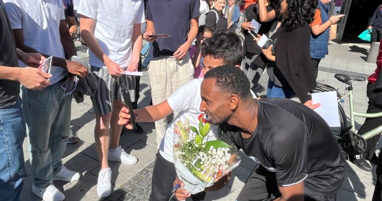 SM-vinnaren Habtom Asgede tar selfie med yngre beundrare på ett torg