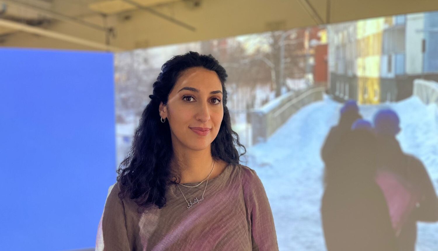 kvinna i projektorljus framför en videoinstallation