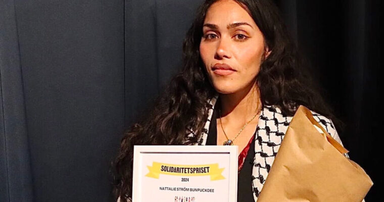 kvinna med palestinasjal håller i ett diplom och en blombukett