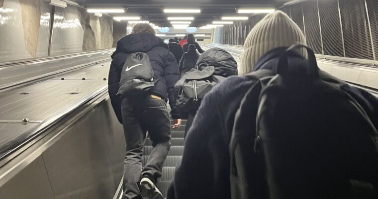 personer går uppför i rulltrappa