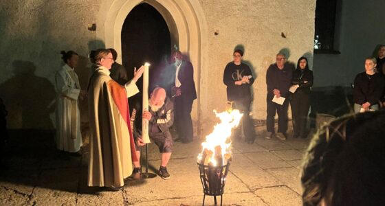 en eld som brinner utanför en kyrka och människor som samlats runt den