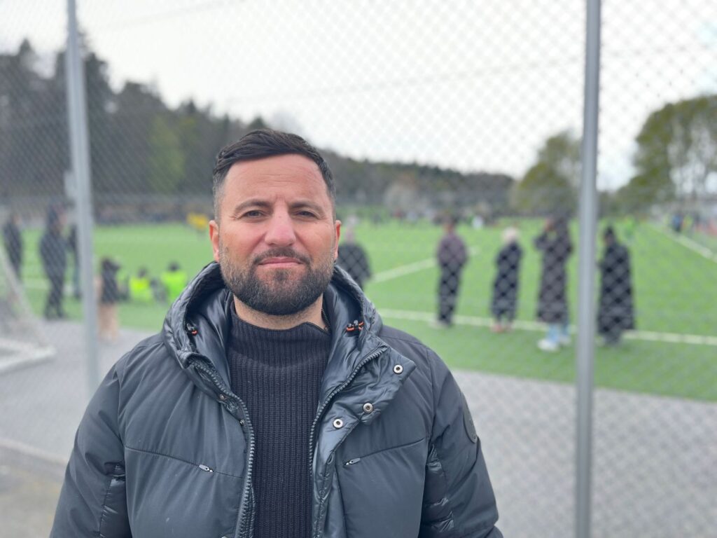 man framför en fotbollsplan med matcher i bakgrunden
