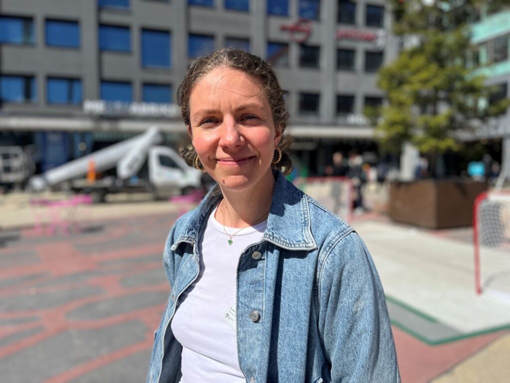 kvinna ler mot kameran på ett soligt torg