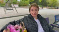 Yvonne på en parkbänk med kasse blommor bredvid sig.