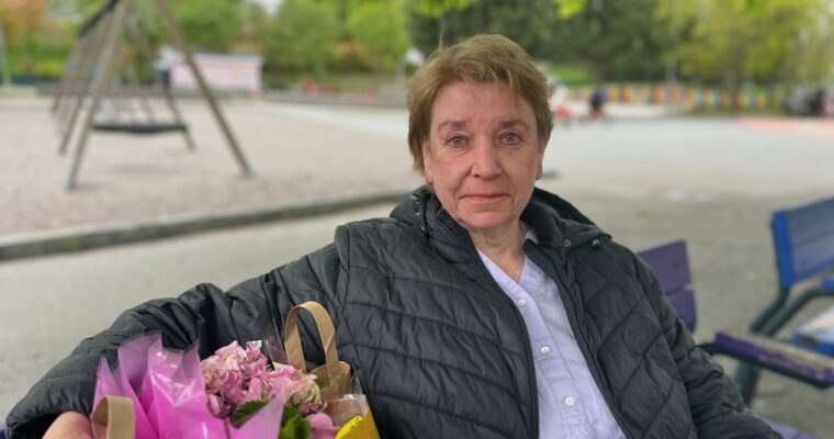 Yvonne på en parkbänk med kasse blommor bredvid sig.