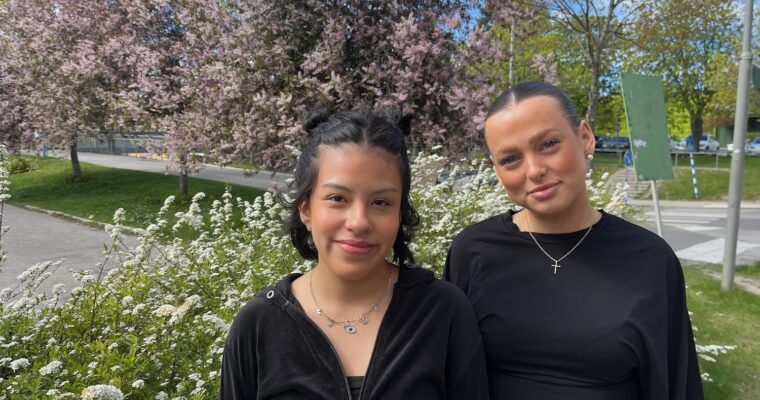 Två leende unga kvinnor fram blommande träd.