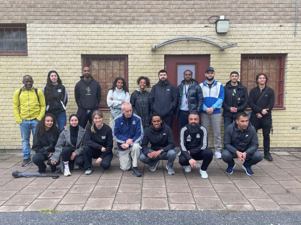 gruppbild av föreningsrepresentanter framför gul tegelbyggnad