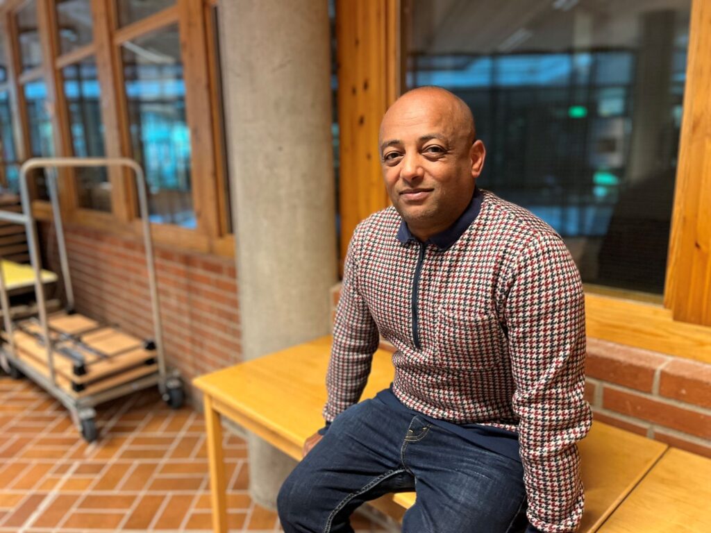 man sitter på en bänk i en skolkorridor