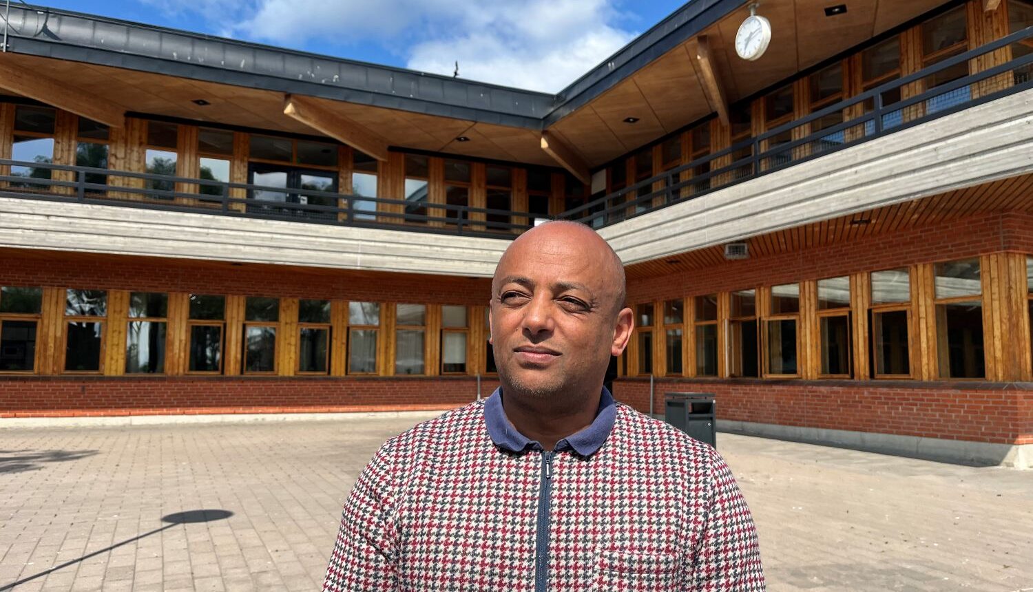 man står i solen framför en gymnasieskola