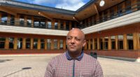 man står i solen framför en gymnasieskola