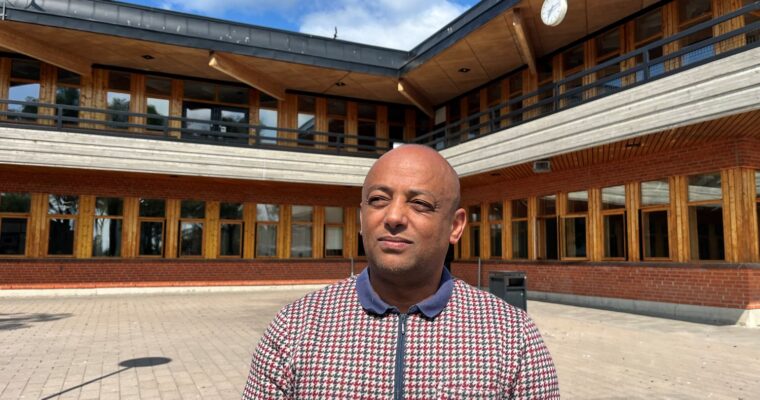 man står i solen framför en gymnasieskola