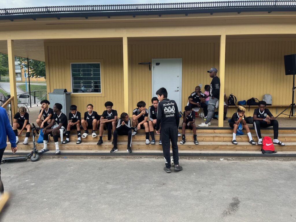 En massa killar sitter i i matchställ på trappan till Knutbys nya laglokal.