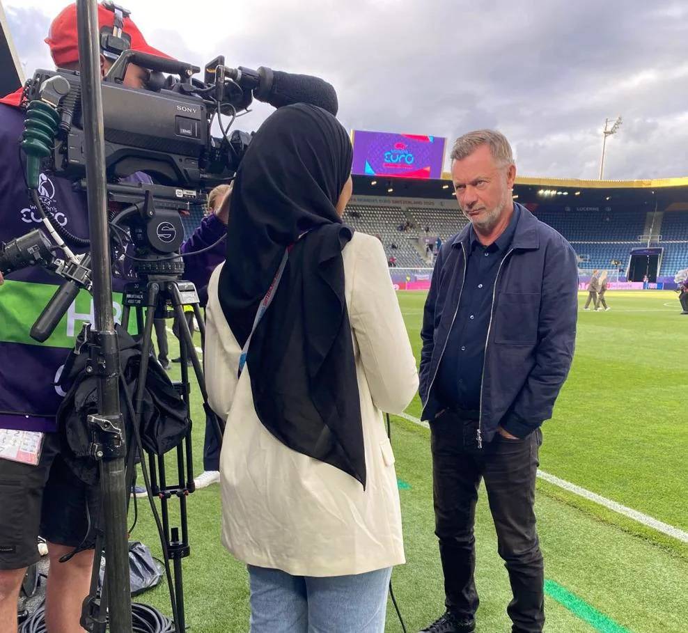 En ung kvinna i hijab intervjuar en medelålders man.