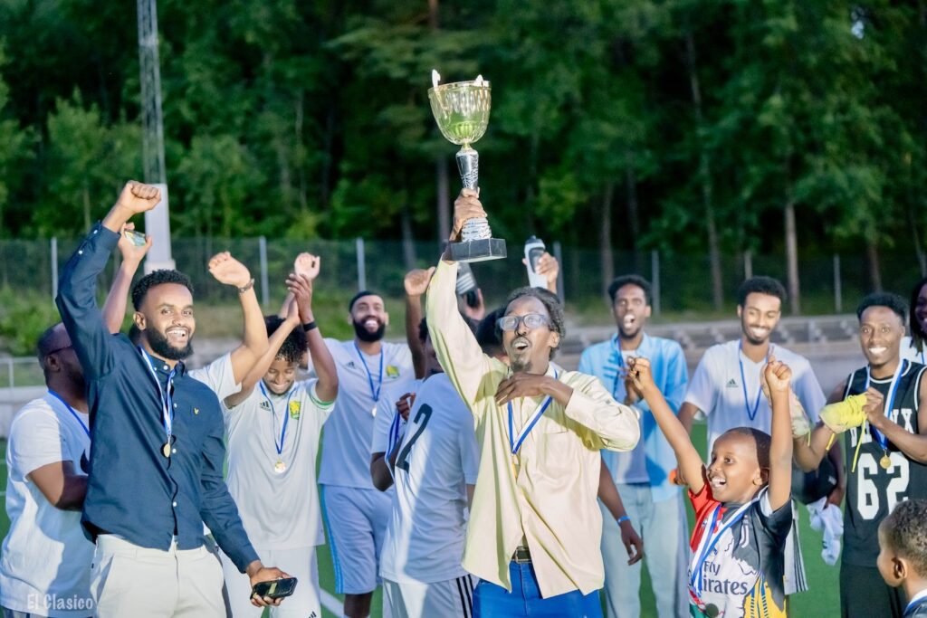 Jublande spelare och tränare med pokalen i skyn.