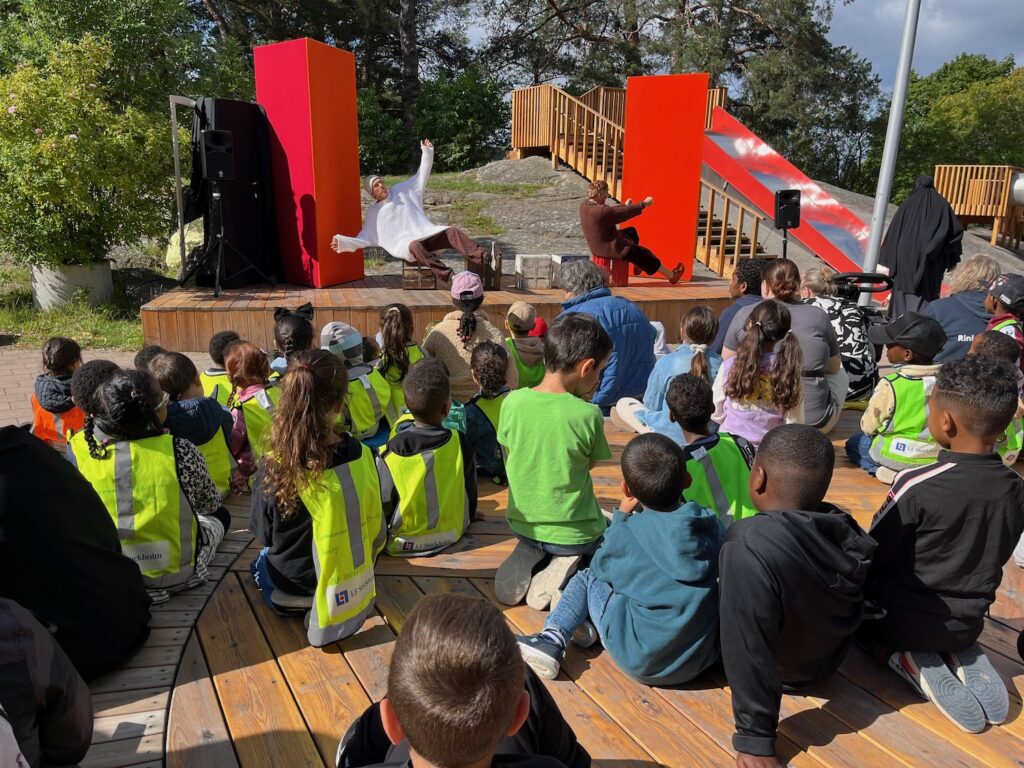 Massa barn som sitter framför scenen.