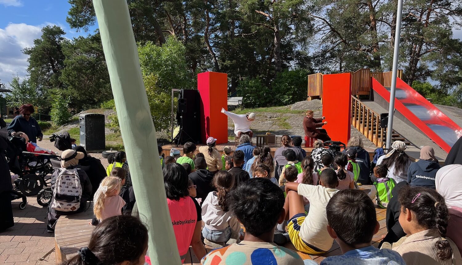 Massa barn som sitter framför scenen.