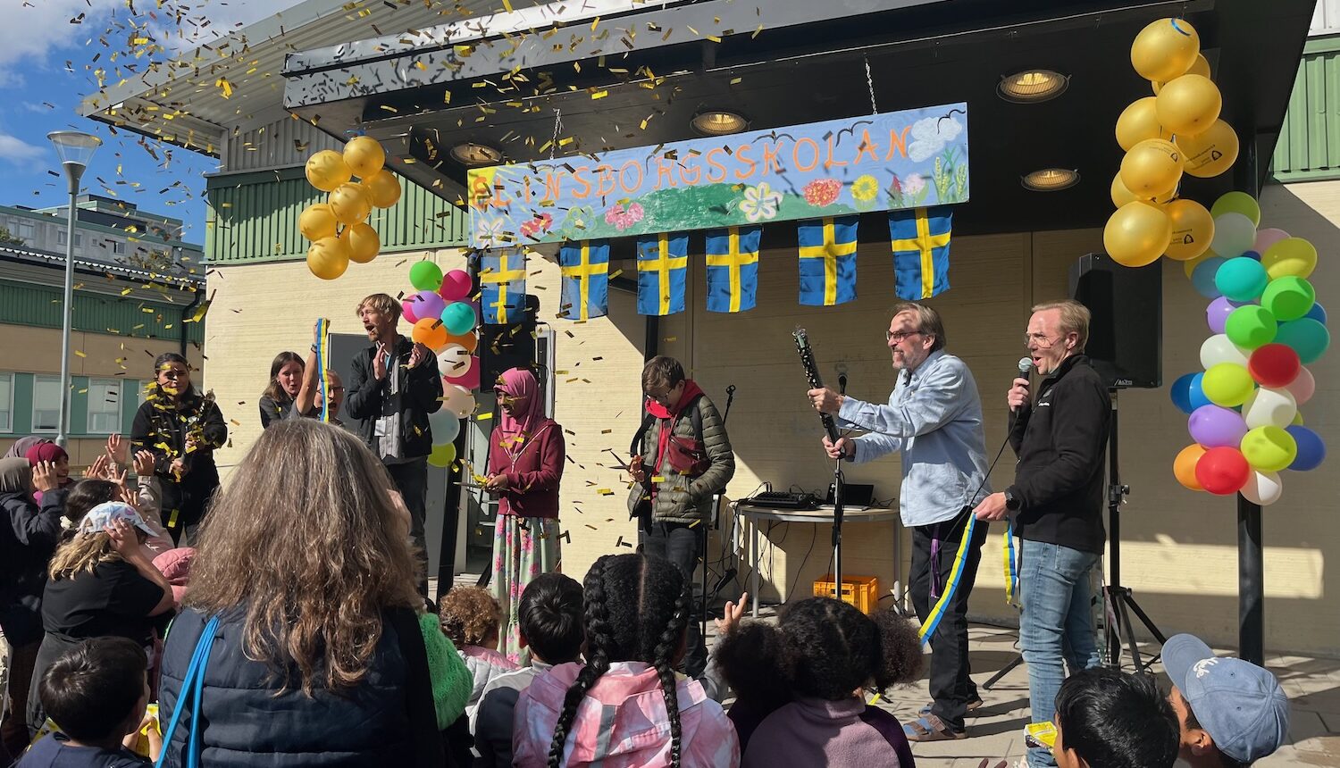 Massa folk på en scen, en tjej klipper bandet och konfetti i luften.