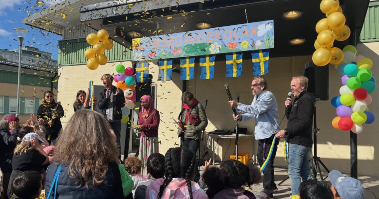 Massa folk på en scen, en tjej klipper bandet och konfetti i luften.