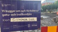En skylt som säger att ombyggnaden av Hjulsta torg ska vara klar sommaren 2025. Bakom stängslet ser man att så inte är fallet.