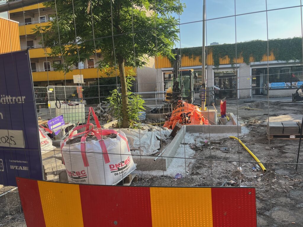 Massa byggmaterial i plastsäckar bakom byggstaket.