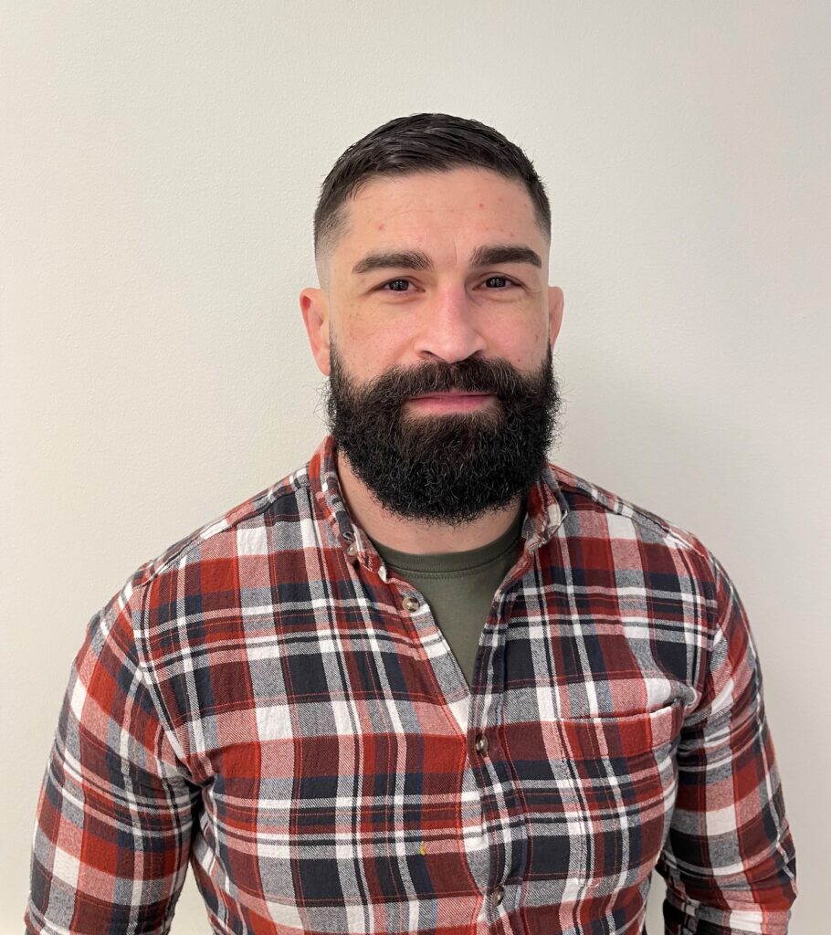 En man i yngre medelålder i skägg och rutig skjorta.