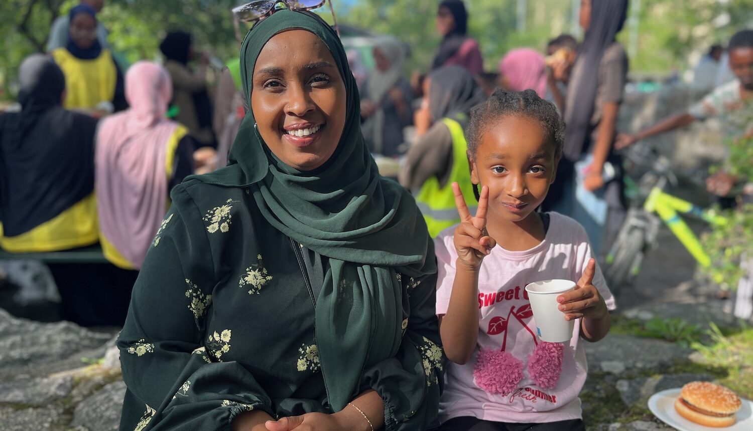 En leende kvinna med sin dotter som gör segertecknet.