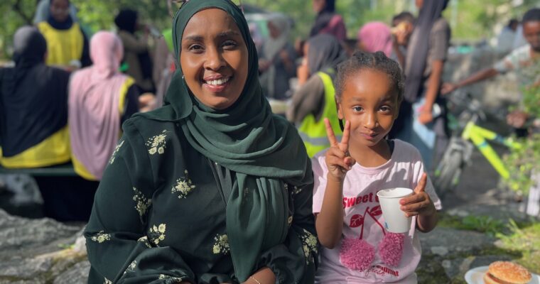 En leende kvinna med sin dotter som gör segertecknet.