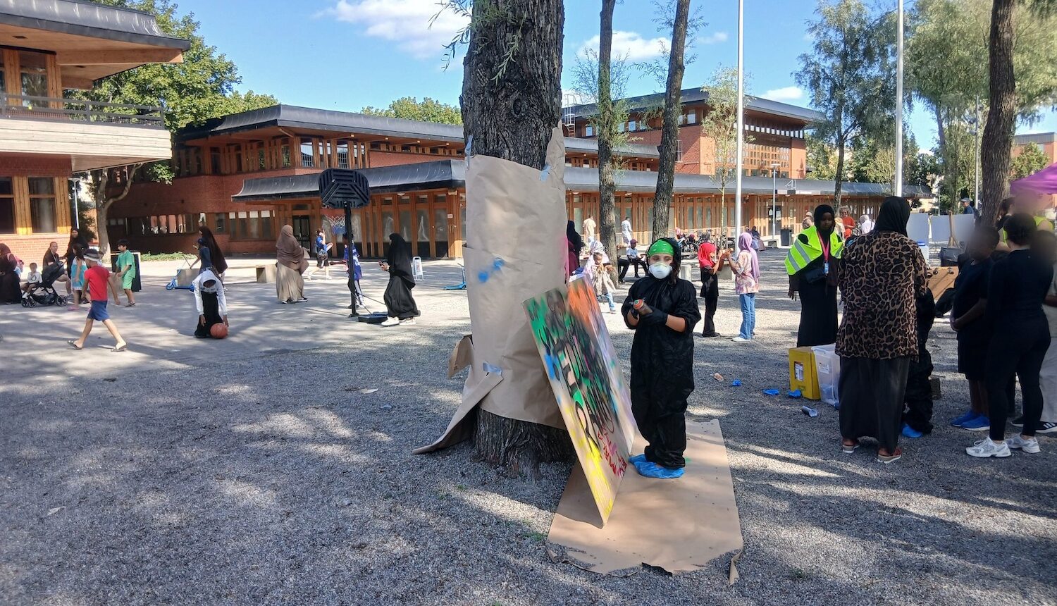 Graffitiplank och en massa folk i parken utanför Tensta träff.