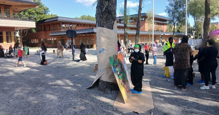 Graffitiplank och en massa folk i parken utanför Tensta träff.
