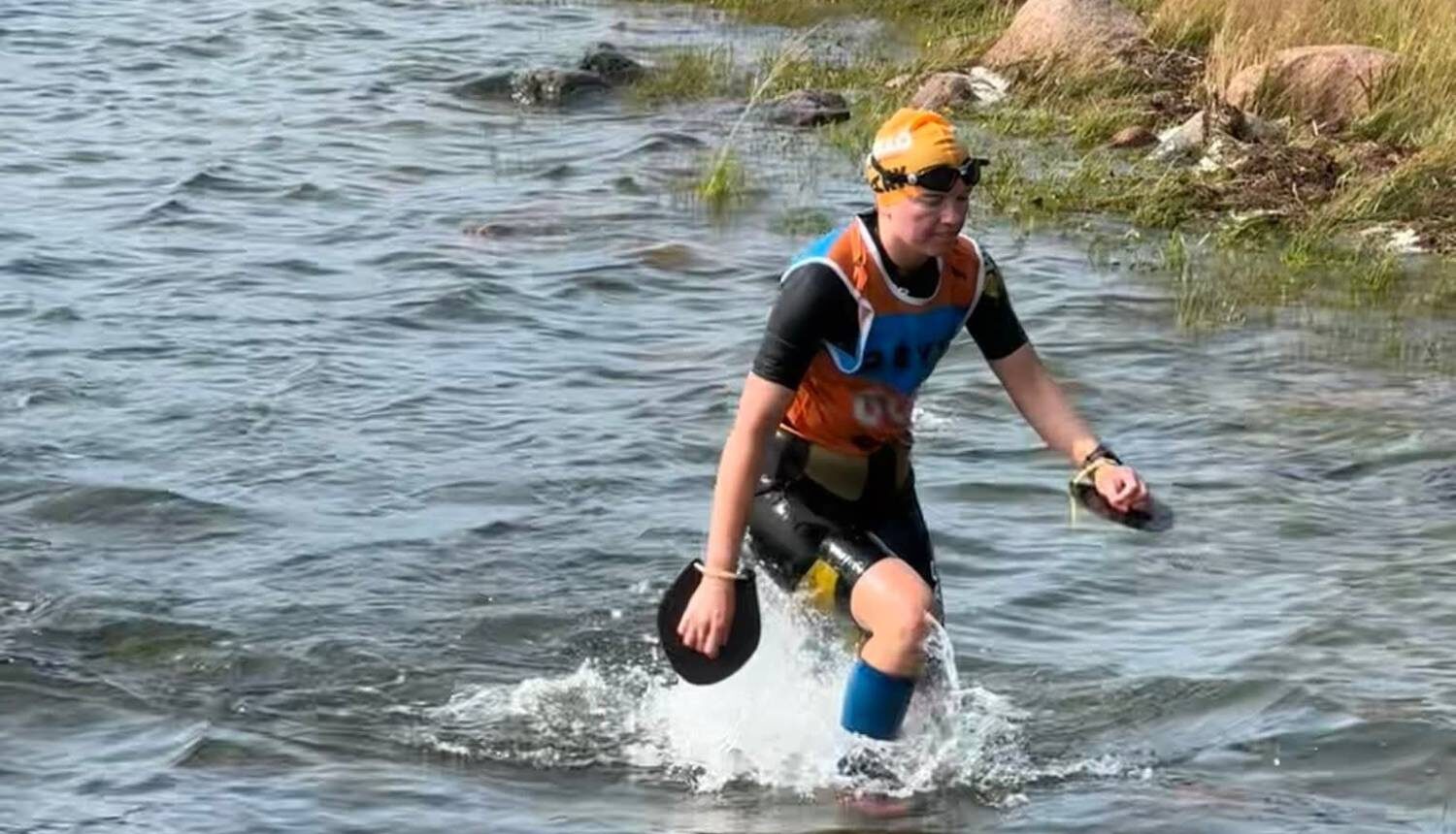 En tjej i badkläder går upp ur havet.