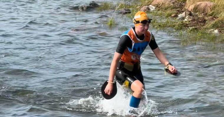 En tjej i badkläder går upp ur havet.