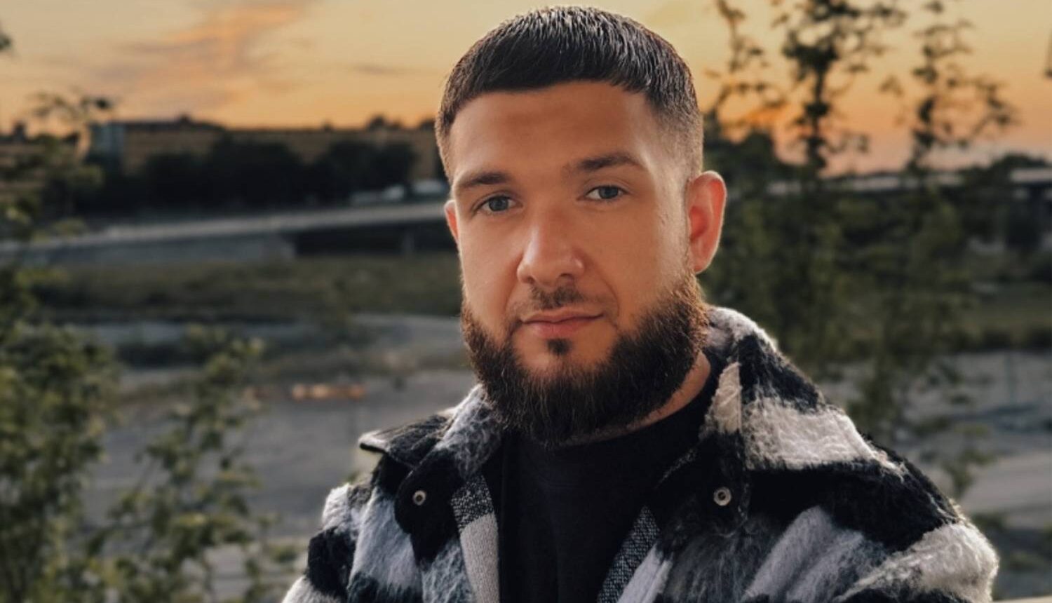 En relativt ung man i ansat skägg tittar rakt in i kameran.