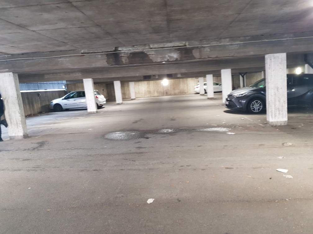 Tre bilar i ett stort garage.