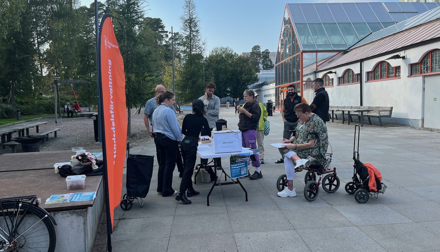 En stående vimpel från stadsdelsförvaltningen och några människor runt ett bord.