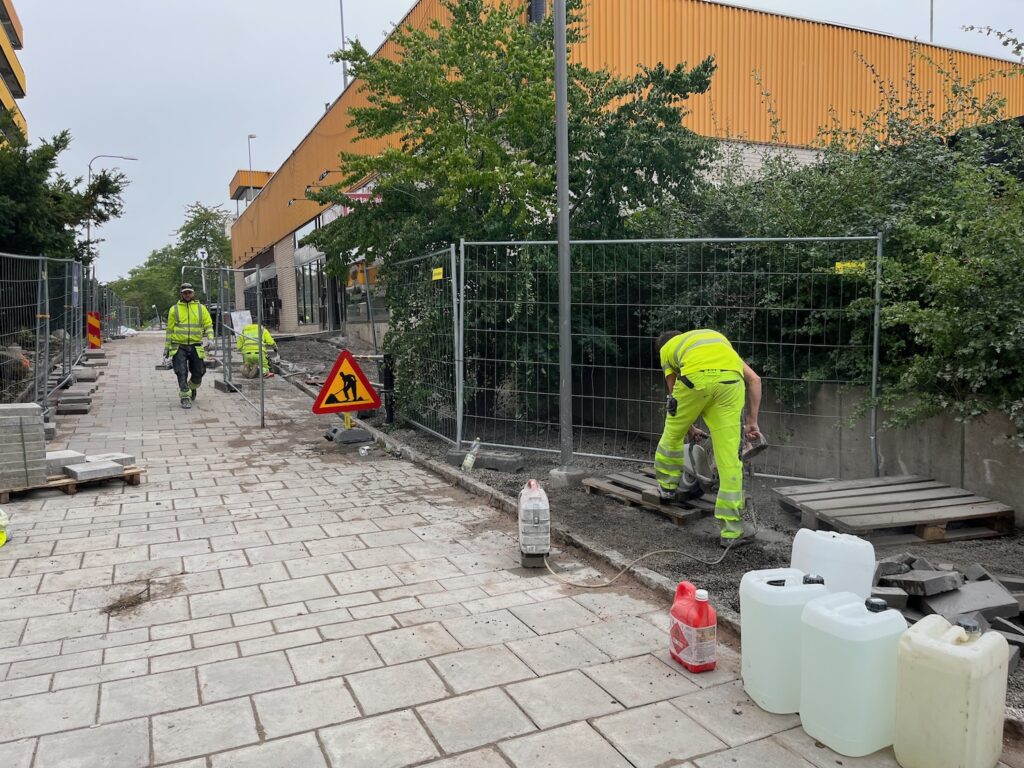 Arbetare som lägger sten längs gångvägen.