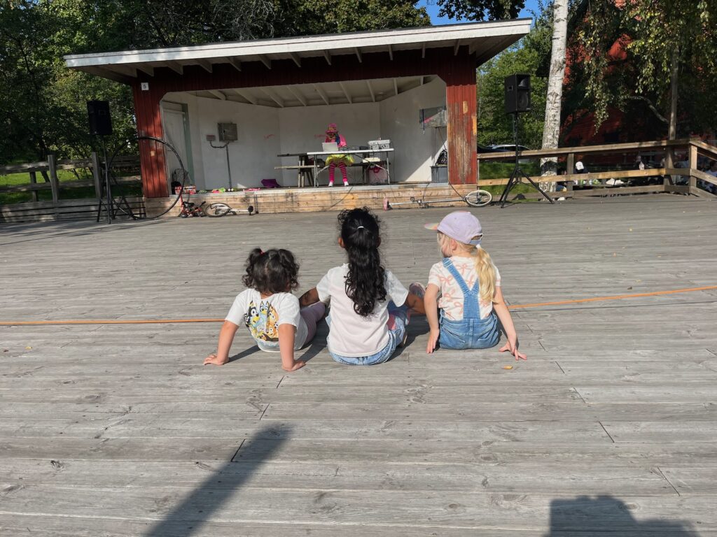 Tre små flickor sitter på dansbanen med ryggen åt fotografen.