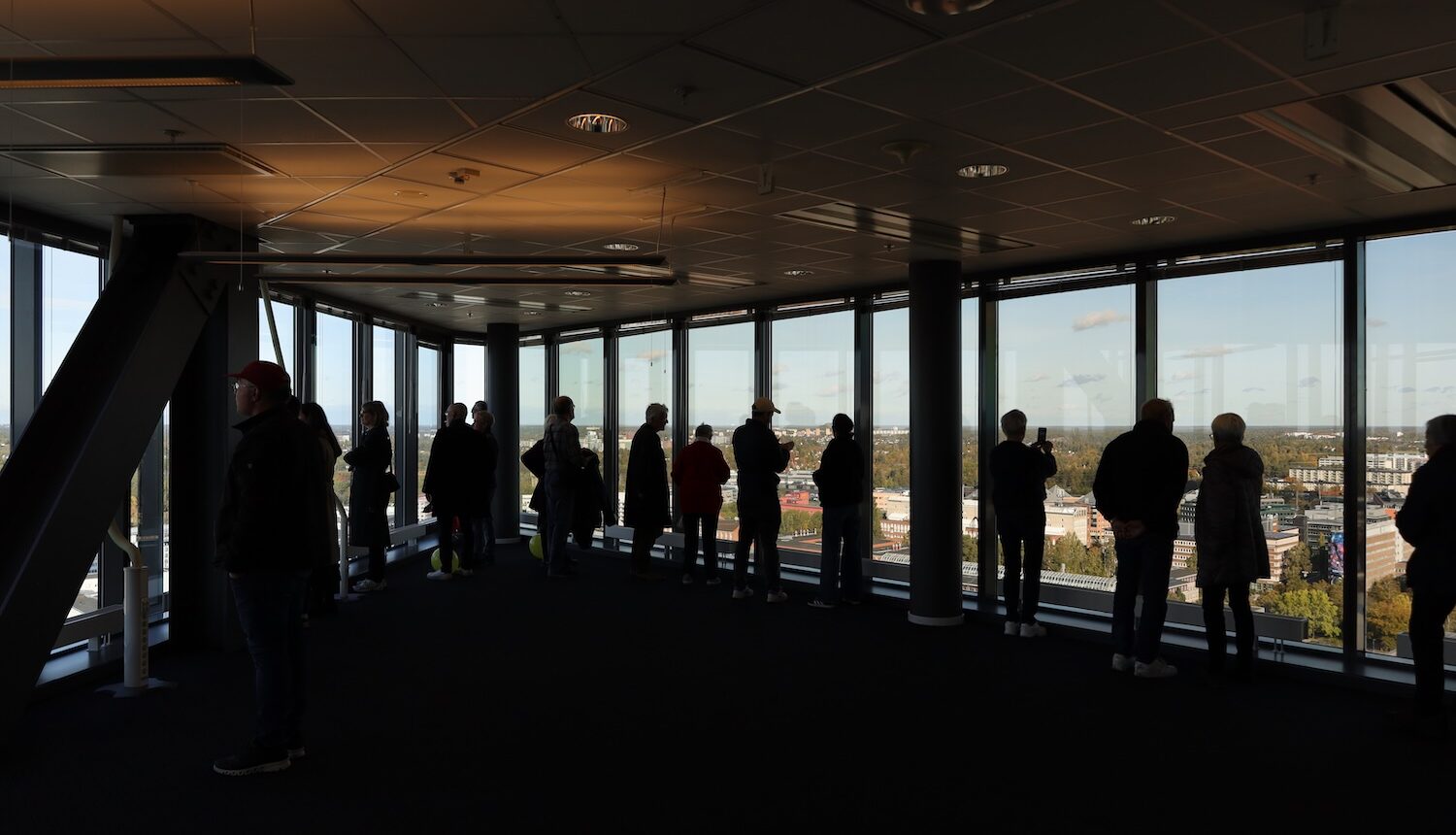 Man ser silhuetterna av människor som står högst upp i Kista Scvience Tower och tittar ut.